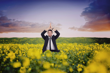 Businessman sitting in lotus pose with hands together against nature sceneの写真素材