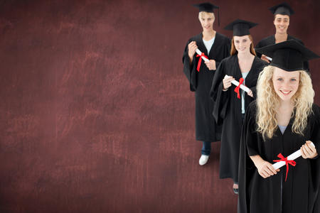 Smiling group of teenagers celebrating after Graduation against deskの写真素材
