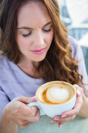 Pretty brunette enjoying a cappuccino on a sunny dayの写真素材