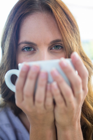 Pretty brunette enjoying a cappuccino on a sunny dayの写真素材