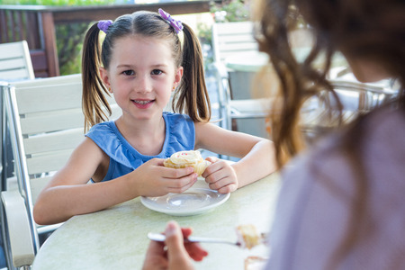 Mother and daughter enjoying cakes at cafe terrace on a sunny dayの写真素材
