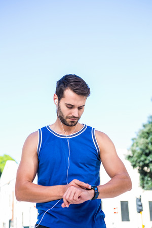 Handsome athlete setting heart rate watch in the cityの写真素材