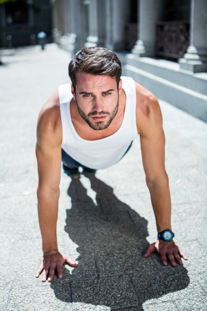 Portrait of handsome athlete doing push ups in the cityの写真素材