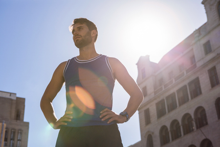 Handsome athlete with hands on hips in the cityの写真素材
