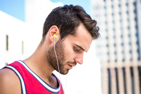 Serious handsome athlete listening to music on a sunny dayの写真素材