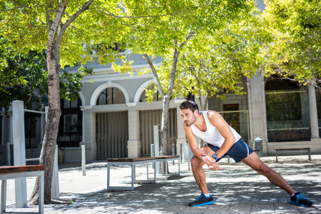 Handsome athlete stretching his leg in the city