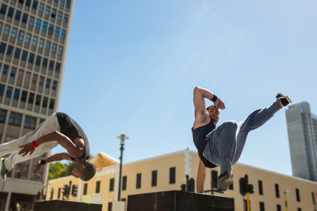Happy friends doing parkour in the city on a sunny dayの写真素材