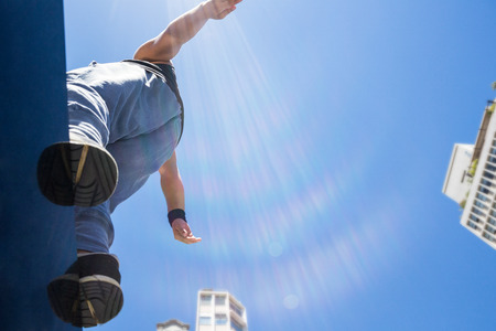 Athletic man about to do a back flip in the cityの写真素材