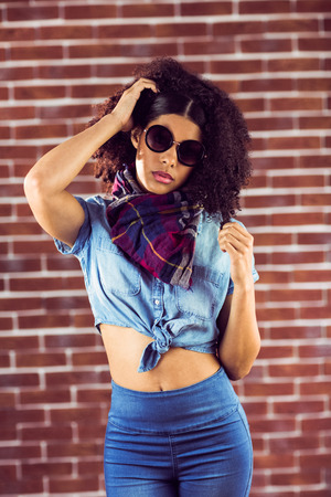 Portrait of attractive young woman playing with hair against red brick backgroundの写真素材