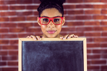 Portrait of a female hipster holding a blackboard against a brick wallの写真素材