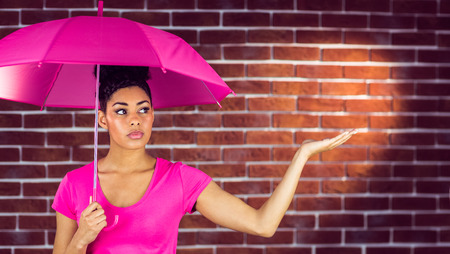 A beautiful woman holding an umbrella against a brick wallの写真素材