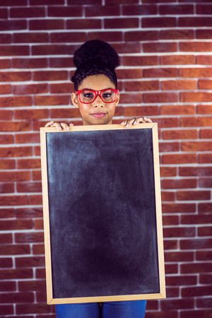 Portrait of a female hipster holding a blackboard against a brick wallの写真素材