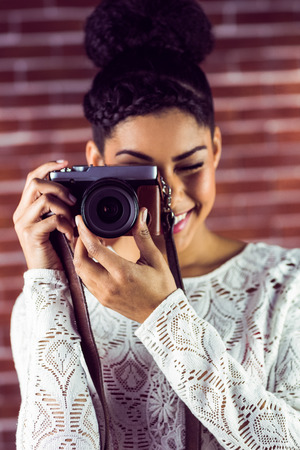 Young hipster taking a picture against a brick wallの写真素材
