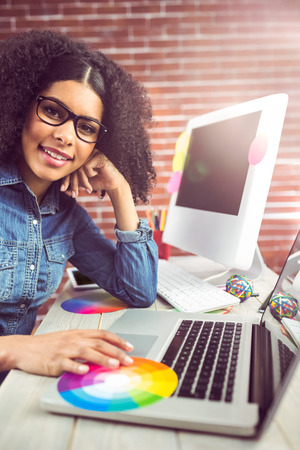Portrait of casual female designer using laptop at workplaceの写真素材