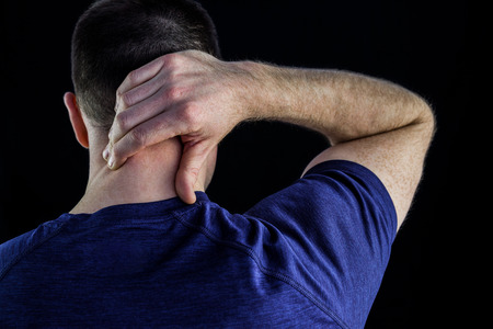 Rear view of a man with neck pain over over black backgroundの写真素材