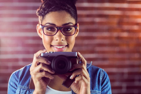 Portrait of a young hipster taking a picture against a brick wallの写真素材