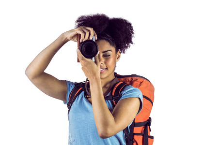 Young woman with backpack taking picture against a white backgroundの写真素材