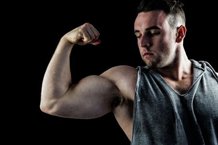Handsome bodybuilder flexing his bicep on black backgroundの写真素材