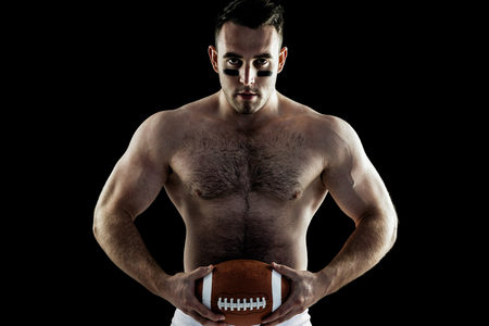 Shirtless American football player with ball on black backgroundの写真素材