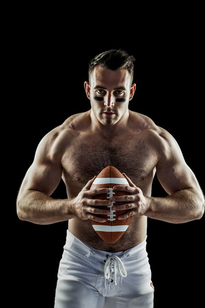 Shirtless American football player with ball on black backgroundの写真素材
