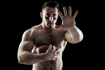 Shirtless American football player with ball on black backgroundの写真素材