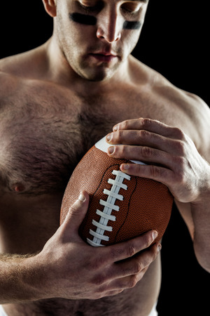 Shirtless American football player with ball on black backgroundの写真素材