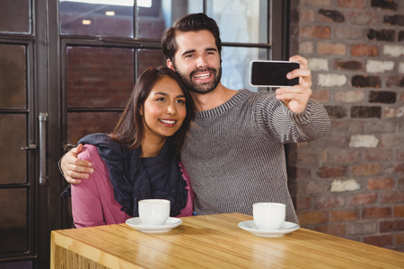 Young happy couple making a selfie in the cafeの写真素材
