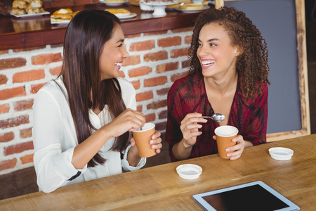 Pretty female friends enjoying a coffee using tablet pc at the coffee shopの写真素材