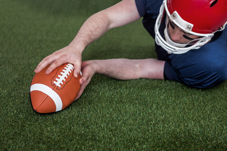 Determined american football player scoring a touchdown on the fieldの写真素材