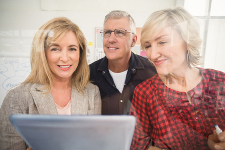 Portrait of a business team working over a tablet at officeの写真素材