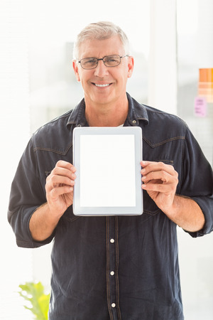 Portrait of a businessman showing a digital tablet at officeの写真素材