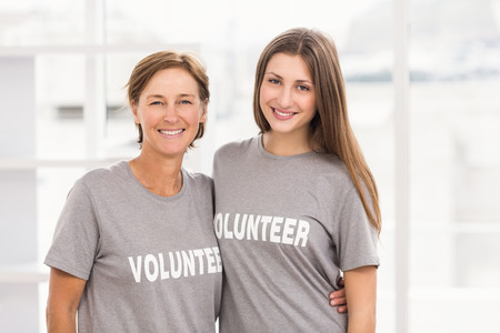 Portrait of smiling female volunteers putting arms around each other in the office