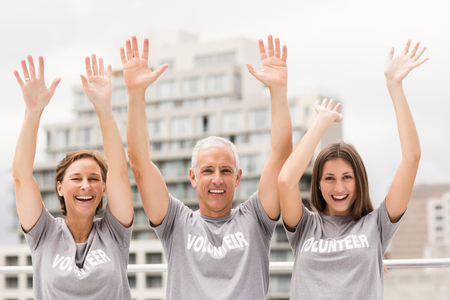 Portrait of smiling volunteers cheering on roof of buildingの写真素材