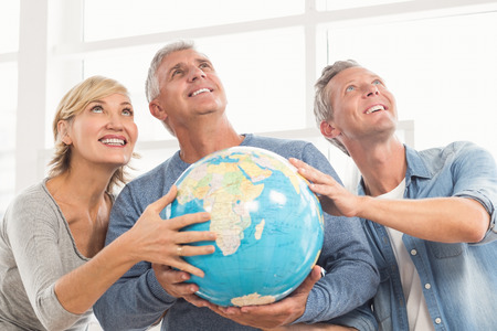Happy business colleagues holding terrestrial globe and looking above