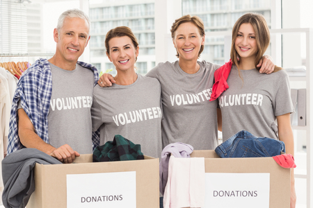 Portrait of smiling volunteers putting arms around each other in the office