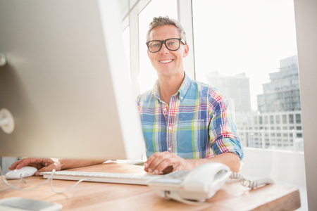 Portrait of smiling casual businessman working with computer in the officeの写真素材