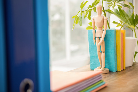 Mannequin and stack of books on wooden window sill in the officeの写真素材