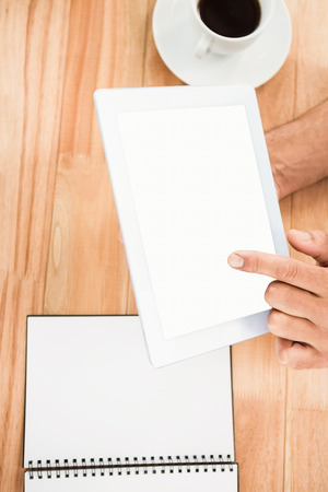 Hands holding blank screen tablet on wooden deskの写真素材