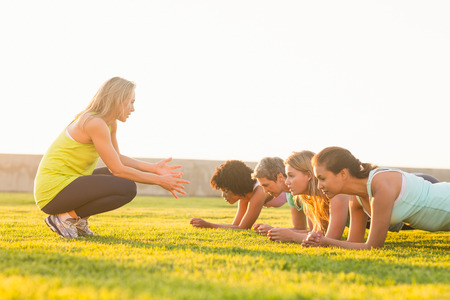 Sporty women planking during fitness class in parklandの写真素材
