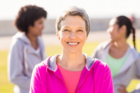 Portrait of smiling sporty woman in front of friends in parklandの写真素材