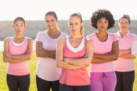 Portrait of women wearing pink for breast cancer with arms crossed in parklandの写真素材