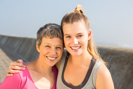 Portrait of sporty mother and daughter smiling at promenadeの写真素材