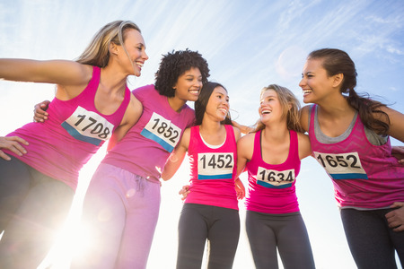 Five smiling runners supporting breast cancer marathon in parklandの写真素材