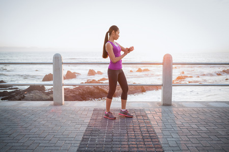 Fit woman checking smart watch at promenade on a sunny day