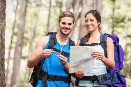 Happy hikers looking at camera holding map and compass in the natureの写真素材