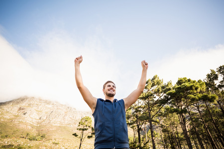 Young happy jogger standing on rock and cheering in the natureの写真素材
