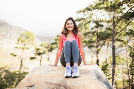 Young happy jogger sitting on rock in the natureの写真素材