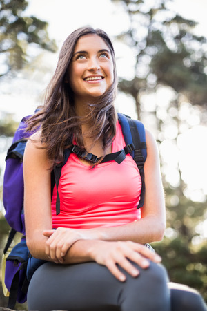 Young happy jogger sitting on rock and looking away in the natureの写真素材