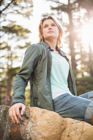 Young happy jogger sitting on rock and looking away in the natureの写真素材
