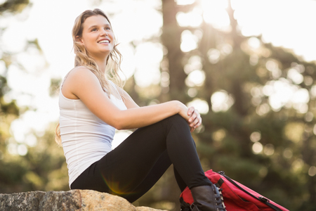 Young happy jogger sitting on rock and looking away in the natureの写真素材
